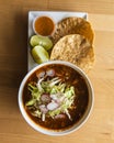 Top view of a bowl of Mexican pozole served with lime and tortilla