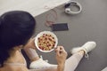 Top view of a bowl of oatmeal with cranberries in the hands of an unknown sports woman.