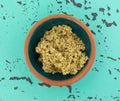 Top view of a bowl with a small portion of crushed sage leaf atop a green and black tabletop