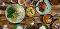 Top view bowl of spicy fish curry sauce and other food on wooden table with Thai rice noodle, vegetable, grilled chicken Royalty Free Stock Photo