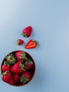 top view of bowl of strawberries on blue background with copy space