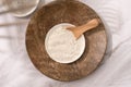 Top view on bowl with white cosmetic clay on wooden tray - mineral powder, bentonite facial mask