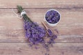 Top view of a bowl and wooden spoons with fresh lavender flowers and a bouquet of lavender on a brown wooden background. Royalty Free Stock Photo