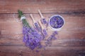Top view of a bowl and wooden spoons with fresh lavender flowers and a bouquet of lavender on a brown wooden background. Royalty Free Stock Photo