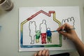 Top view of a boy painting a picture of a family in a house