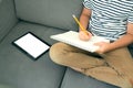 Top view on boy writing or drawing and using his tablet while doing homework. Studying online during quarantine, online training Royalty Free Stock Photo