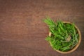 Top view, branches of fresh rosemary in Wooden cup on wooden rustic background.