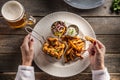 Top view of breaded chicken nuggets with french fries, dip, salad and a beer served on a plate held by female hands Royalty Free Stock Photo
