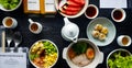 Top view of breakfast with fresh salad, dim sum, noodle with boiled pork, watermelon, dragon fruit, bottle of orange juice