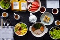 Top view of breakfast with fresh salad, dim sum, noodle with boiled pork, watermelon, dragonfruit, bottle of orange juice