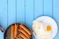 Top view of breakfast meal ,Fried sausages in black pan and fried eggs in white dish on blue wooden table, have copy space for put Royalty Free Stock Photo