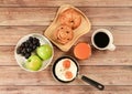 Top view of breakfast set , black coffee , orange juice, fried eggs,danish pastry and croissant, two apples and grape on wooden Royalty Free Stock Photo