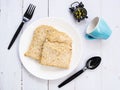 Top view of breakfast set with whole wheat bread on a ceramic plate, coffee cup, alarm clock and cutlery on wooden table Royalty Free Stock Photo