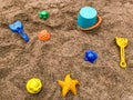 Top view of bright colored plastic molds, shovel, rake and bucket in the sandbox, against the background of dark sand with Royalty Free Stock Photo