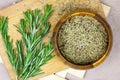 Top view of bright fresh green and dried rosemary branches, twigs and leaves in a wooden bowl and board on light background. Royalty Free Stock Photo