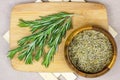 Top view of bright fresh green and dried rosemary branches, twigs and leaves in a wooden bowl and board on light background. Royalty Free Stock Photo