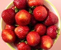 Top view of bright freshly picked strawberries on pink background