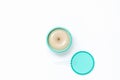 Top view of a bright turquoise jar with cosmetic cream next to which lies a lid with a spatula on a white background. The concept Royalty Free Stock Photo