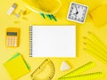 Top view of bright yellow office desktop with blank notepad, sch