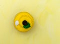 Top view of a brightly frosted cupcake on a yellow background