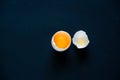 top view of broken egg shell with a yolk on a black background, copy space Royalty Free Stock Photo