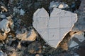 Top view of a broken piece of gray tile with a shape of heart on small stones