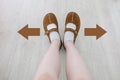 Top View of Brown Boot with Different Brown Decision Arrow. A Pair of Feet Standing. Shoes Walking Direction on Wooden