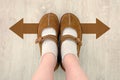 Top View of Brown Boot with Different Brown Decision Arrow. A Pair of Feet Standing. Shoes Walking Direction on Wooden