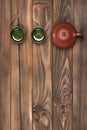 Brown ceramic teapot and two dark green small special cups on a dark wooden planked background. Tea ceremony.