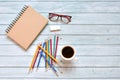 Top view of brown closed cover blank notebook with coffee cup with eyeglasses and various colorful pencil on wood table background Royalty Free Stock Photo