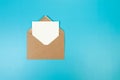 Top view of brown Kraft envelope, white card on blue background.