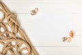 top view of brown nautical knotted rope and empty paper with seashells on white wooden surface Royalty Free Stock Photo