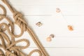 top view of brown nautical knotted rope and empty paper with seashells on white wooden surface Royalty Free Stock Photo