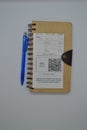 Top view of a brown notebook made of recycled paper with a blue pen and a receipt on a white background. Royalty Free Stock Photo