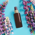 Top view of brown spray bottle mockup and multicolor lupines on a turquoise blue background. Blank label bottle for branding. Royalty Free Stock Photo