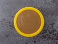 Top view of brown turkey gravy in a small yellow bowl on a gray background