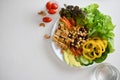Top view, Buddha bowl mixed vegetables with grilled tofu on a white table with a glass of water Royalty Free Stock Photo