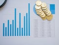 Top view of a bunch of coins over a paper full of graphics and charts, representing economy and finances Royalty Free Stock Photo