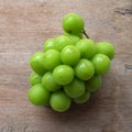 bunch of fresh sweet green shine muscat (vitis vinifera) grape isolate on a wooden background. japanese grapes. Royalty Free Stock Photo