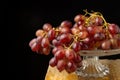 Top view of bunch of wet red grapes on glass cake stand on wooden table, selective focus, black background Royalty Free Stock Photo