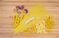 Uncooked various pasta and wheat ears on the wooden surface Royalty Free Stock Photo