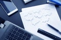 Top view of business chart on black table with with laptop, phone, pen, ruler and stapler