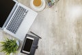 Top view of business desk with laptop, mobile phone, coffee, potted plant, notebook and business accessories