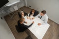 Top view of 4 business people sitting at a table and discussing blueprints. Designers engineers at a meeting. Royalty Free Stock Photo