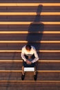 Top view of business professional using blank screen laptop and looking at his smartwatch while sitting on outdoor steps Royalty Free Stock Photo