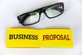 Top view of business proposal text on yellow notepad with glasses on white cover background. Business concept Royalty Free Stock Photo