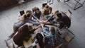 Top view of business team working at trendy loft office. Young mixed race group of people puts palm together on centre. Royalty Free Stock Photo