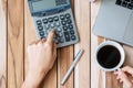 Top view Business woman hand holding coffee cup and calculating with calculator, pen and computer laptop on wood office desk table Royalty Free Stock Photo