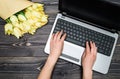 Top view of business woman hands typing on open laptop computer keyboard and bouquet of yellow tulips, copy space. Womens day Royalty Free Stock Photo