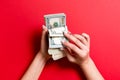 Top view of a businesswoman`s hands counting one hundred and different dollar banknotes on colorful background. Success and wealt